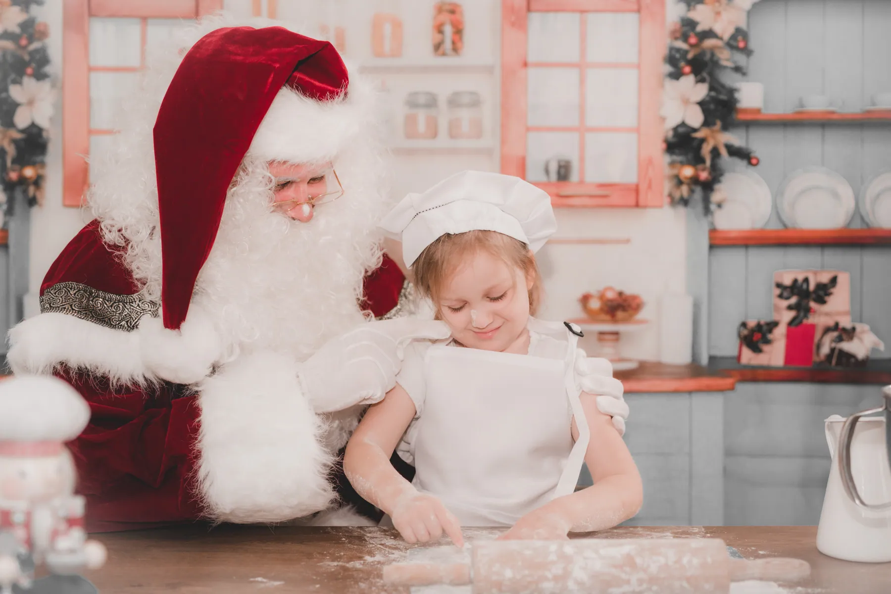 Mädchen backt mit dem Weihnachtsmann in der Weihnachtsbäckerei
